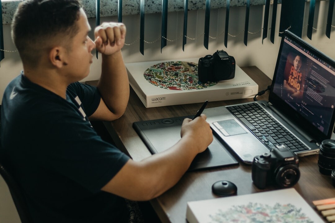 Journalist working at a desk with photos and a laptop reviewing celebrity news